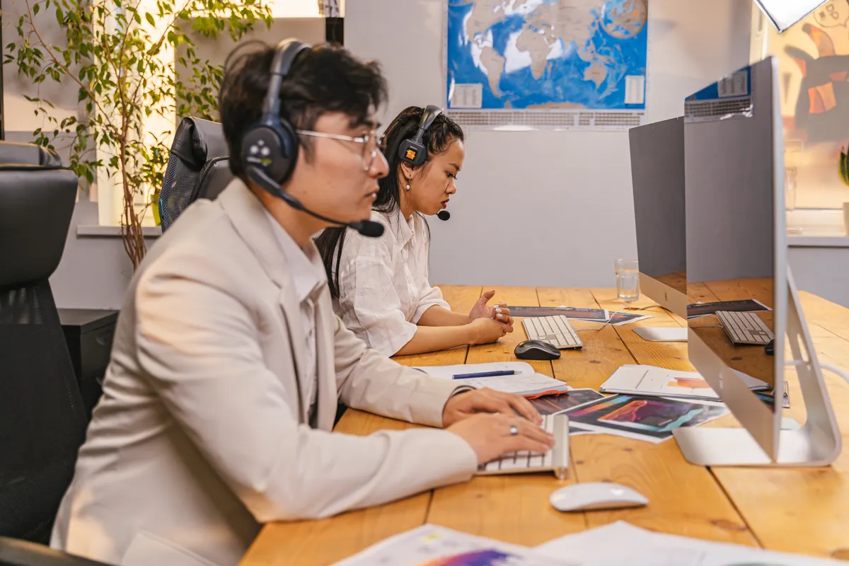 Customer support colleagues working at computers while wearing headsets.