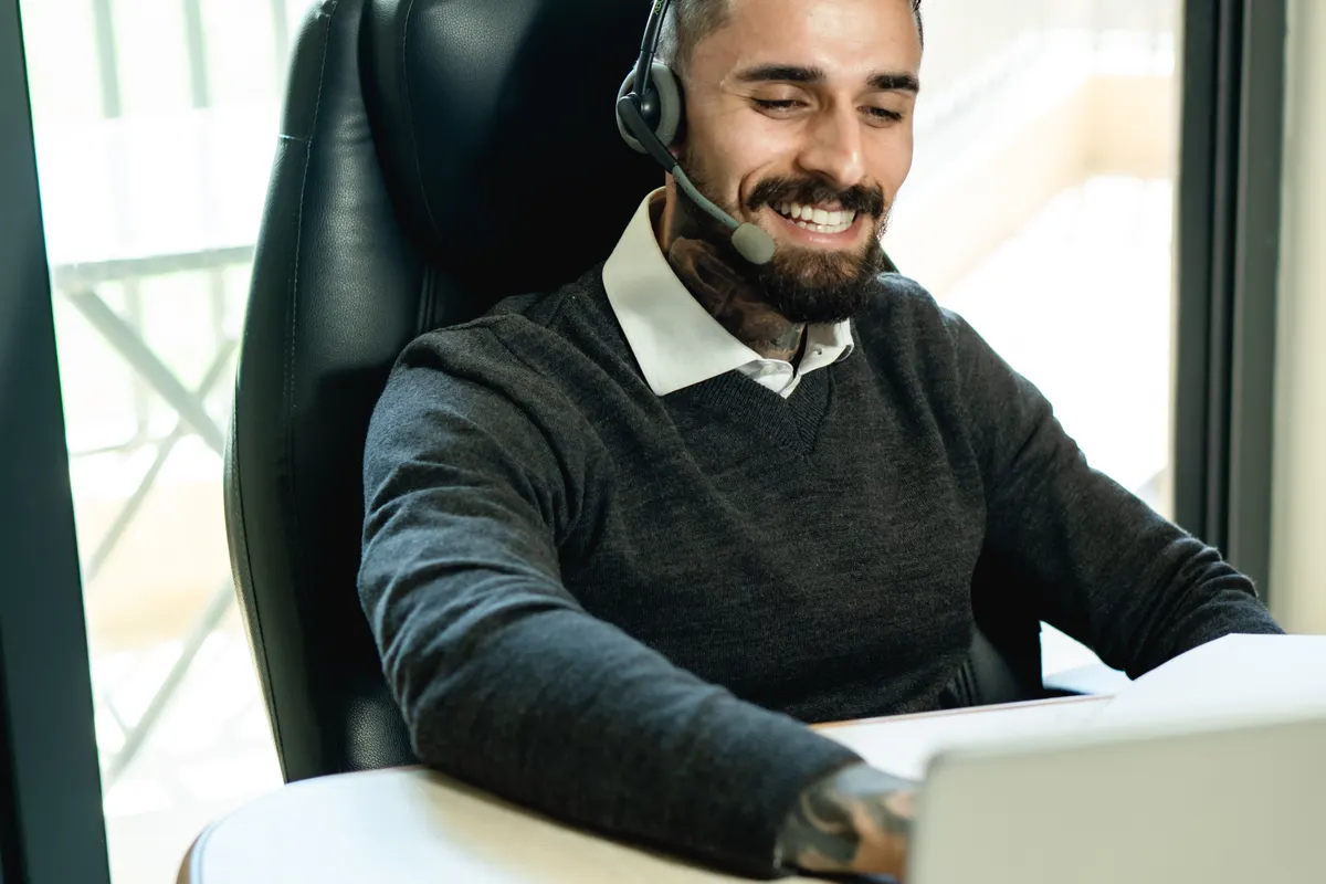 Receptionist wearing a headset while working at a laptop.